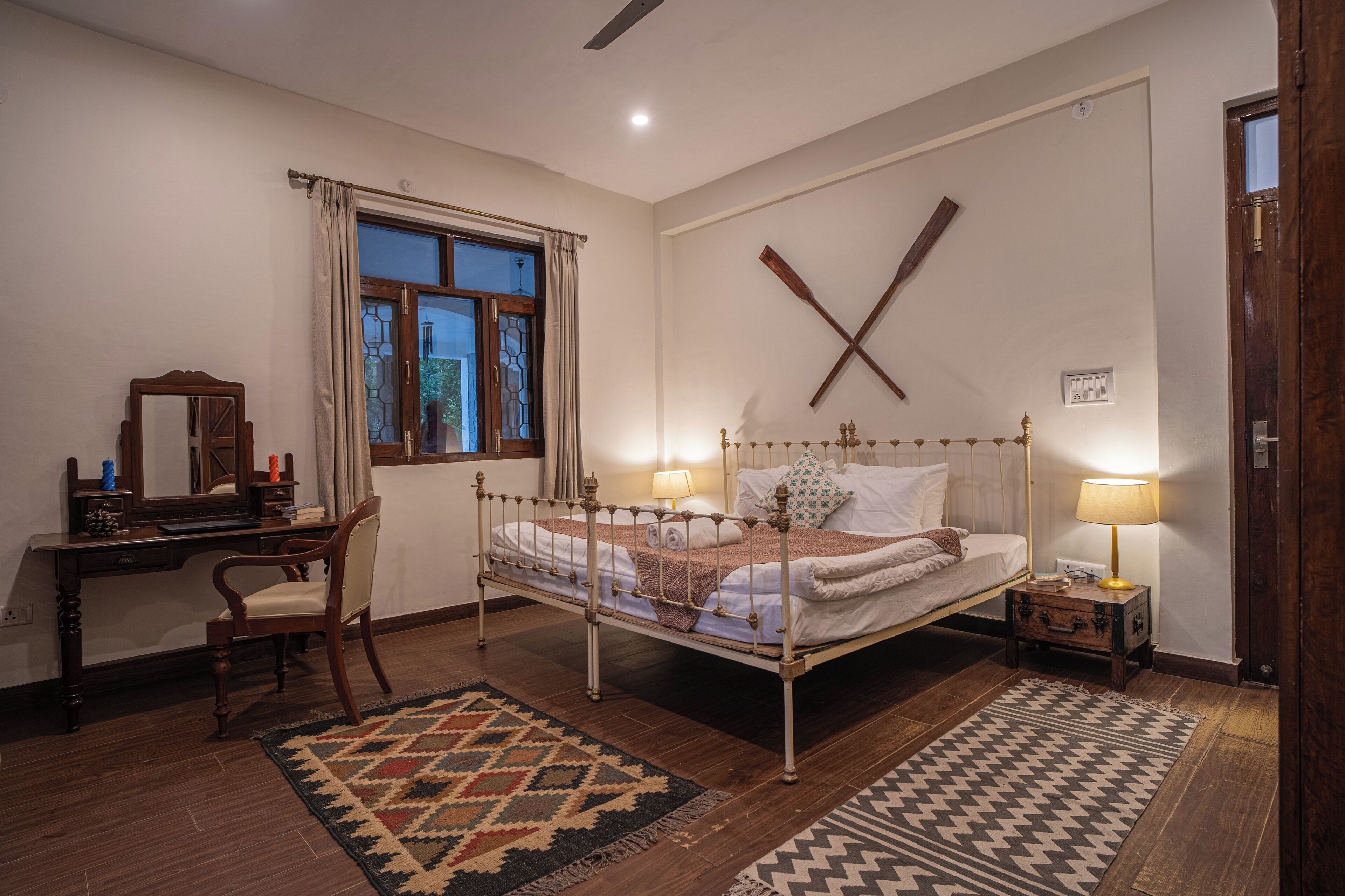 A bedroom with a bed, desk, chair, and two nightstands with lamps.