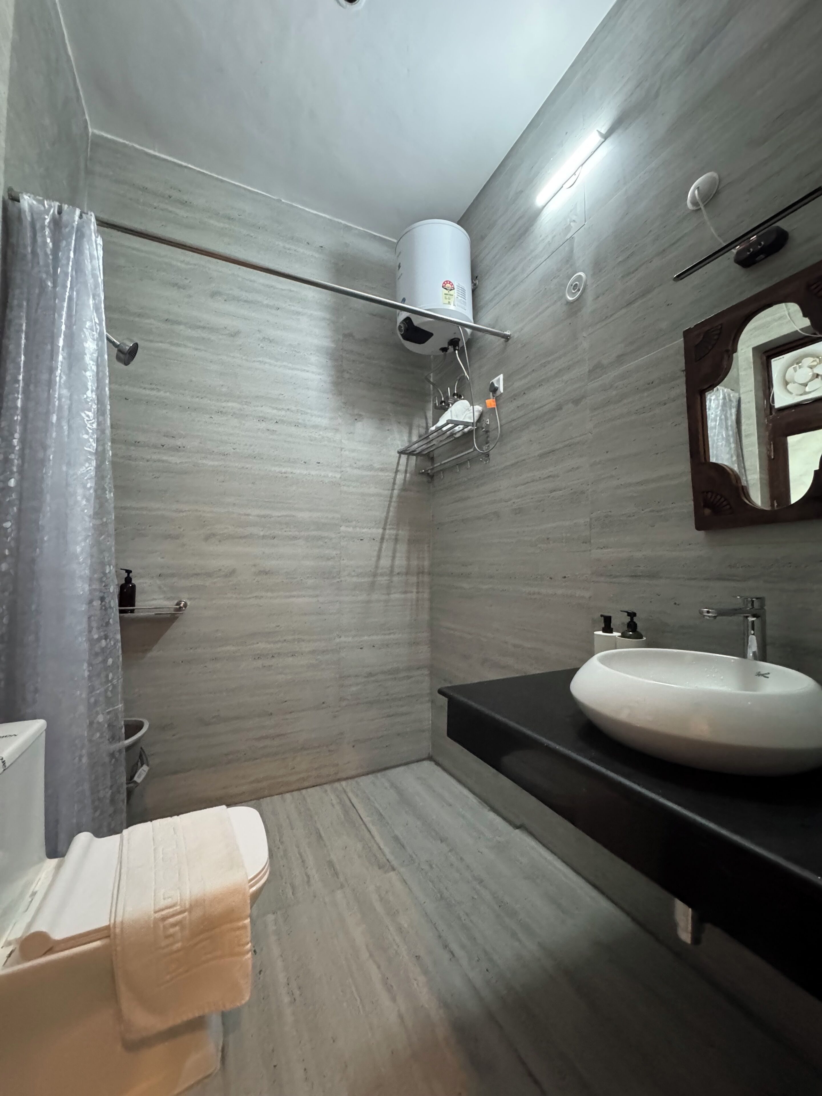 A bathroom with a white sink, a mirror with a decorative frame, a towel rack, a shower curtain, and a towel on the floor.