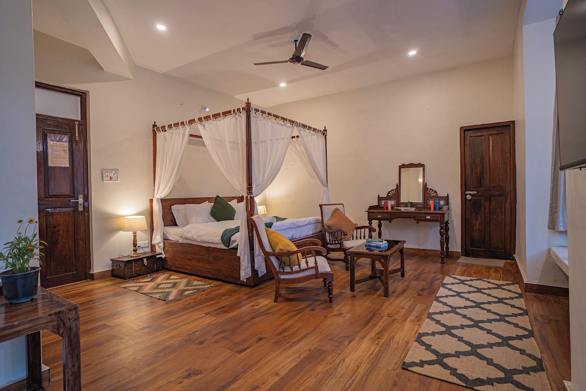 Une chambre à coucher avec un lit à baldaquin, un bureau avec un miroir et une chaise.