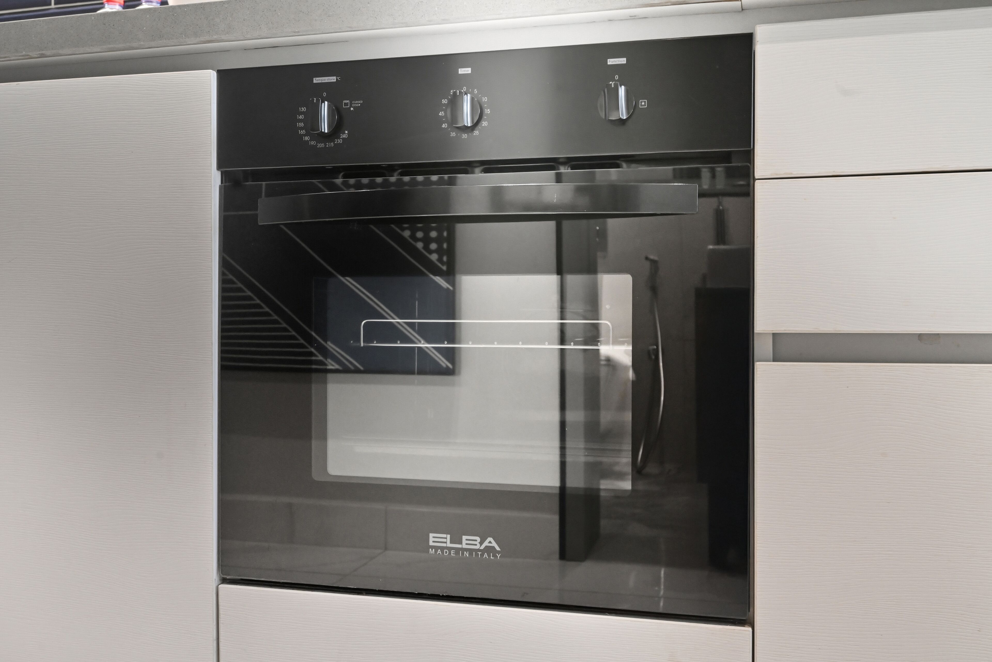 Um forno de aço inoxidável com porta de vidro, com a inscrição "ELBA MADE IN ITALY".