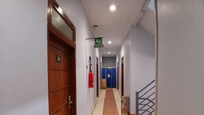 A hallway with a fire extinguisher, a blue door, and a staircase. - Tamastu Hotel Fortuna Jatiwaringin (Bekasi)