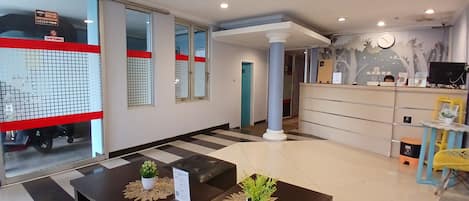 A reception area with a desk, chairs, a potted plant, and a wall clock.