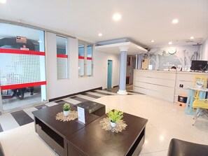 A reception area with a check-in counter, a waiting area with a coffee table, and a reception desk. - Tamastu Hotel Fortuna Jatiwaringin (Bekasi)