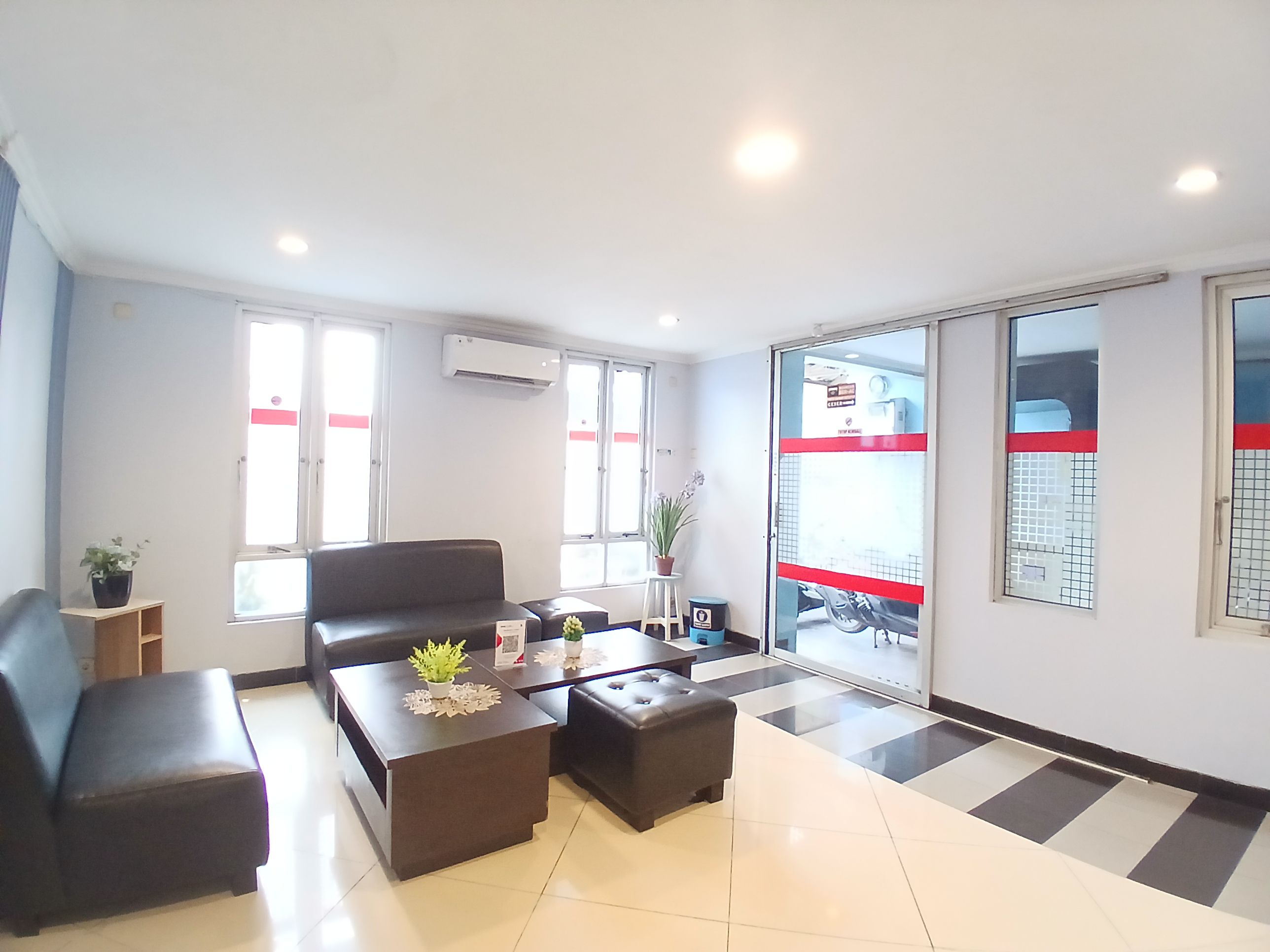 A modern waiting area with a sofa, two coffee tables, and a potted plant.