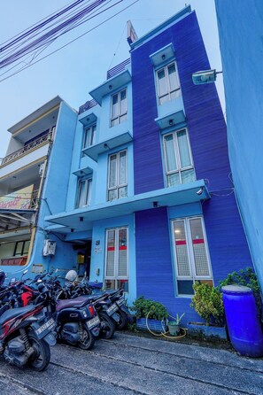 A multi-story building with a blue facade, multiple windows, and a ground-level entrance. - Tamastu Hotel Fortuna Jatiwaringin (Bekasi)