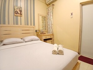 Una habitación de hotel con una cama, mesita de noche, espejo, ventana con cortinas y puerta.