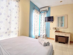 Ein Hotelzimmer mit einem Bett, einem Nachttisch, einem Spiegel, einer Klimaanlage und Vorhängen.