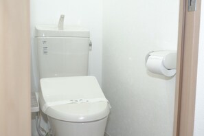Ein kleines, weißes Badezimmer mit Toilette und Papierhandtuchspender.