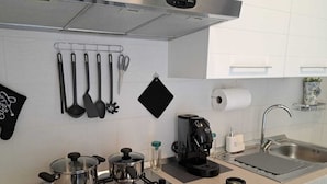 Una cucina moderna con elettrodomestici in acciaio inossidabile, una macchina da caffè e diversi utensili esposti a parete.
