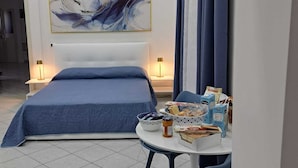 Una camera da letto con un letto, un tavolo rotondo con sedie, un quadro appeso al muro e una finestra con tende.