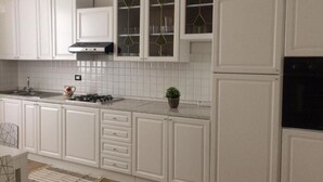 Una cocina moderna con armarios blancos, estufa a gas y un salpicadero de azulejos.