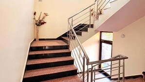 Uma escadaria com guarda-corpos de metal e um vaso de flores à esquerda.