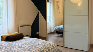 Une chambre à coucher avec un lit, un miroir et un luminaire suspendu.