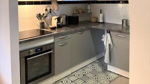Une cuisine moderne avec des meubles gris, un four encastré, un grille-pain et un pare-feu en carreaux.