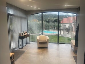Una sala de estar moderna con un amplio ventanal corredero que da a una zona de piscina.