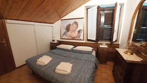 A bedroom with a bed, a nightstand, a dresser, a window with blinds, and a framed picture on the wall. - Edolo Apartment (Edolo)