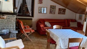 A cozy room with a red sofa, a dining table with a white tablecloth, and a brick wall. - Edolo Apartment (Edolo)