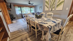 A dining area with a table covered in a patterned tablecloth, surrounded by white chairs. - Spacious 3 bedroom 1.5 bath house in sunny Palm Bay near Space Coast- sleeps 8 (Palm Bay)