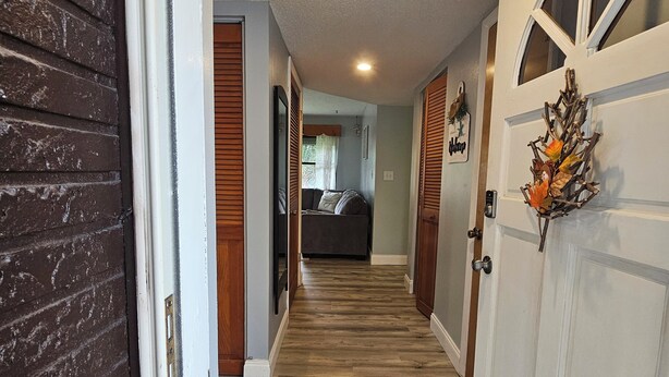 A hallway with wooden flooring, white doors, and a bed in the background. - Spacious 3 bedroom 1.5 bath house in sunny Palm Bay near Space Coast- sleeps 8 (Palm Bay)