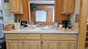 A kitchen with wooden cabinets, a marble countertop, and various coffee-related items. - Spacious 3 bedroom 1.5 bath house in sunny Palm Bay near Space Coast- sleeps 8 (Palm Bay)