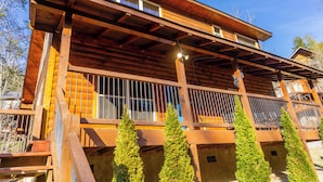 A wooden cabin with a balcony, large windows, and a wooden deck. - 1 Mi to Parkway! Hot Tub Hideaway in Pigeon Forge (Pigeon Forge)