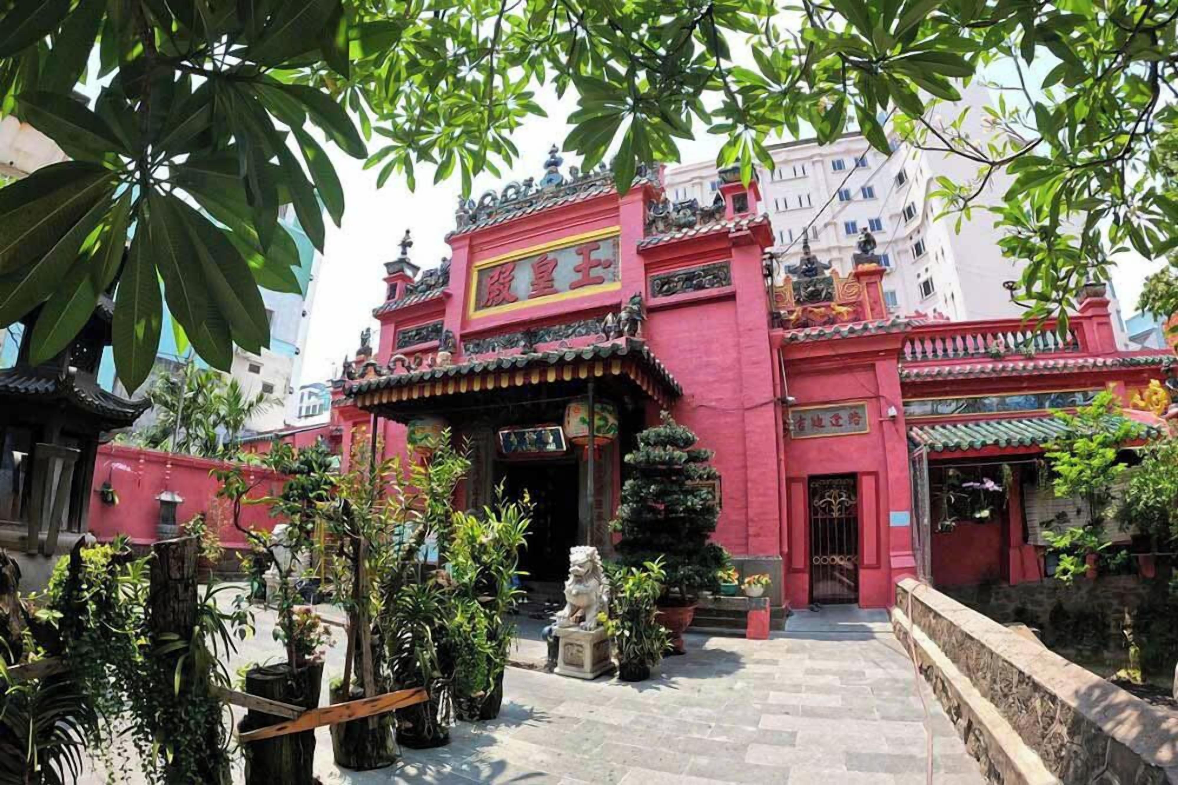 Un edificio tradicional chino con fachada roja, techo de tejas y una estatua en su parte frontal.