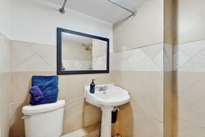 A bathroom with a toilet, sink, and mirror. - Lake of the Ozarks Apt 3 Mi to Dtwn Shops & Dining (Lake Ozark)