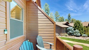 A wooden deck with two Adirondack chairs, a wooden railing, and a view of a backyard with trees and a lawn. - Golf, Trails & Lakes! Show Low Home w/ Bonus Suite (Show Low)