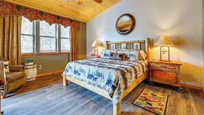 A bedroom with a wooden ceiling, a bed with a patterned blanket, two bedside tables with lamps, and a window with curtains. - Golf, Trails & Lakes! Show Low Home w/ Bonus Suite (Show Low)