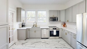 A modern kitchen with white cabinetry, a marble floor, and stainless steel appliances. - < 2 Mi Dtwn Augusta: Charming Historic Home (Augusta)