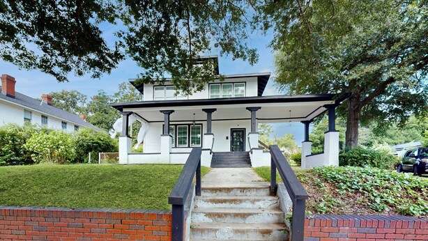 A two-story house with a front porch, a brick wall, and a staircase leading to the entrance. - < 2 Mi Dtwn Augusta: Charming Historic Home (Augusta)