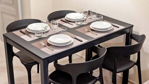 A dining table set for four with black chairs, clear glassware, and white plates. - Located in the heart of the city, within an elegant residential building, ‘La Maison des Étoile’ offers a unique living experience for those seeking comfort and style in perfect harmony.With its minimalist and modern décor, it welcomes you with a k (La Spezia)