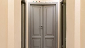 A closed double door with a handle, set in a hallway with plain walls and a tiled floor. - Located in the heart of the city, within an elegant residential building, ‘La Maison des Étoile’ offers a unique living experience for those seeking comfort and style in perfect harmony.With its minimalist and modern décor, it welcomes you with a k (La Spezia)