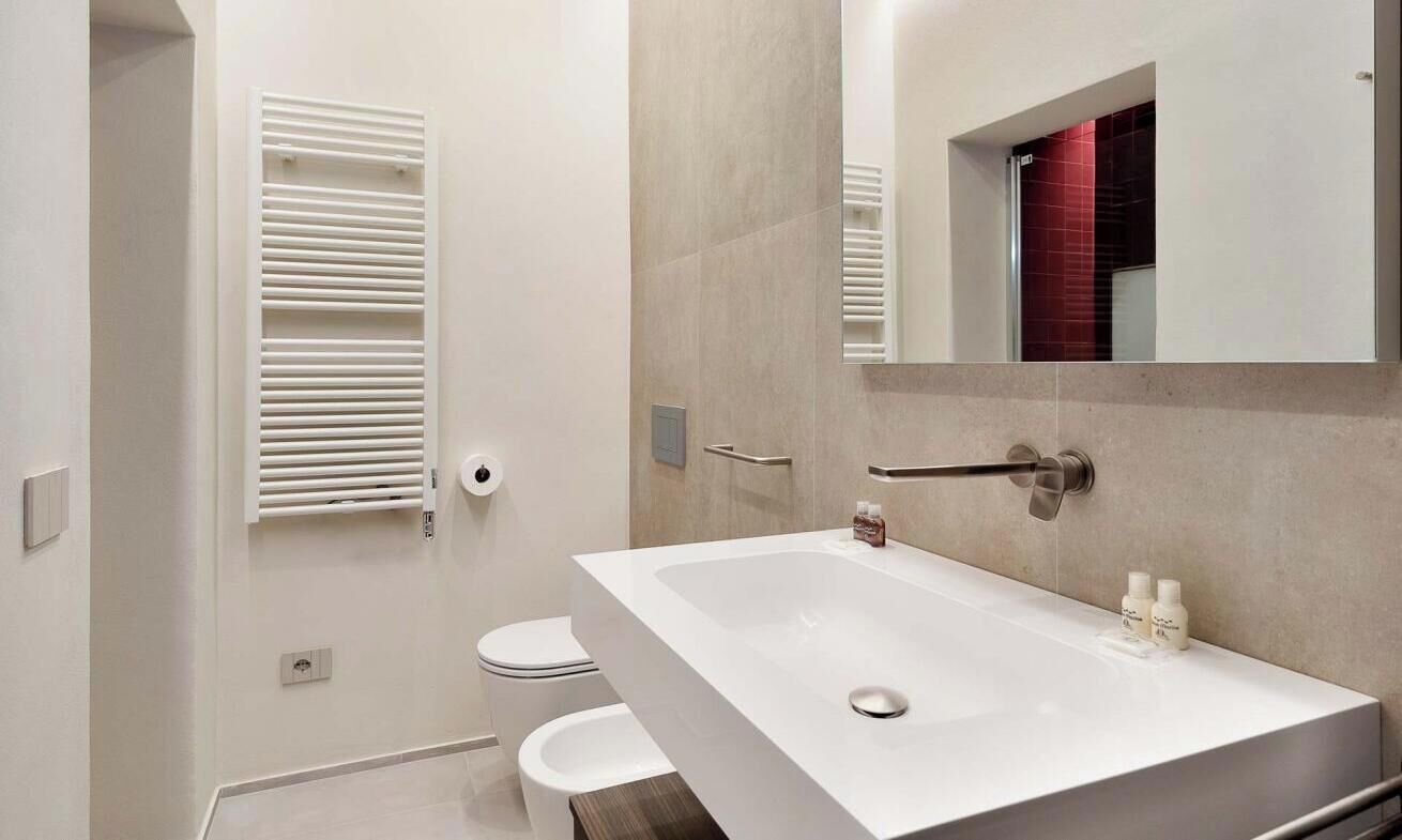 Une salle de bain moderne avec un lavabo blanc, un miroir et des toilettes.