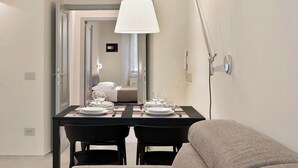 A hotel room with a dining area featuring a table set for two, a sofa, and a mirror reflecting the room. - Located in the heart of the city, within an elegant residential building, ‘La Maison des Étoile’ offers a unique living experience for those seeking comfort and style in perfect harmony.With its minimalist and modern décor, it welcomes you with a k (La Spezia)