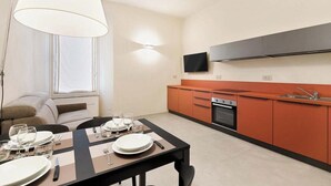 A modern kitchen with orange cabinets, a black countertop, and a built-in oven. - Located in the heart of the city, within an elegant residential building, ‘La Maison des Étoile’ offers a unique living experience for those seeking comfort and style in perfect harmony.With its minimalist and modern décor, it welcomes you with a k (La Spezia)