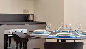 Une cuisine moderne avec une table à manger mise pour quatre personnes, comprenant assiettes, verres et couverts.
