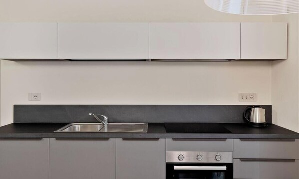 Een moderne keuken met een zwart aanrecht, een roestvrijstalen spoelbak en een ingebouwde oven.