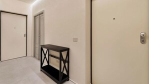 Un couloir avec deux portes, une console noire et un interrupteur sur le mur.