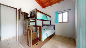 Habitación con literas, techo de madera, ventana con cortinas y suelo de baldosas.