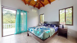 Una camera da letto con un letto, un comodino, una ventola a soffitto e una finestra vista verde.