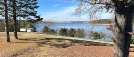 Une vue sur le lac, avec des arbres, un quai et un bâtiment au loin.