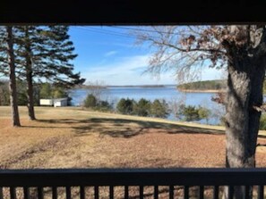 A lakeside view with trees, a dock, and a building in the distance. - Sunset Point at Greers Ferry Lake! (Heber Springs)