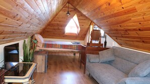 A cozy attic bedroom with a loft bed, a sofa, a wooden table, and a window providing natural light. - Quinta do Ribeiro Real (Estreito de Câmara de Lobos)