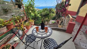 A patio with a tiled table and chairs, surrounded by potted plants and a view of the sea. - Quinta do Ribeiro Real (Estreito de Câmara de Lobos)