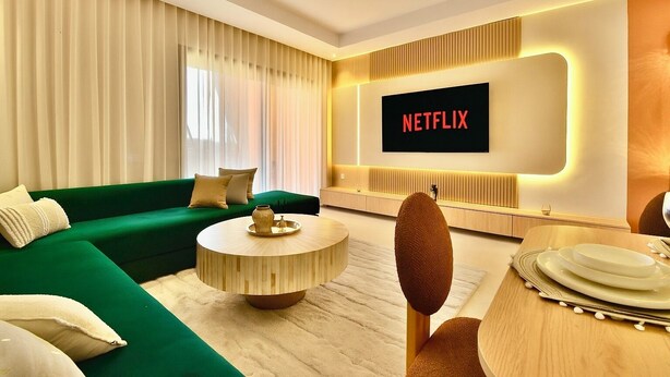 A modern living room with a green sofa, a round coffee table, and a flat-screen TV displaying "NETFLIX". - Modern 2BR/2BA Apt • Pool View Terrace • Fast Fiber WiFi • Noria Resort (Marrakech)