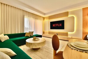 A modern living room with a green sofa, a round coffee table, and a flat-screen TV displaying "NETFLIX". - Modern 2BR/2BA Apt • Pool View Terrace • Fast Fiber WiFi • Noria Resort (Marrakech)