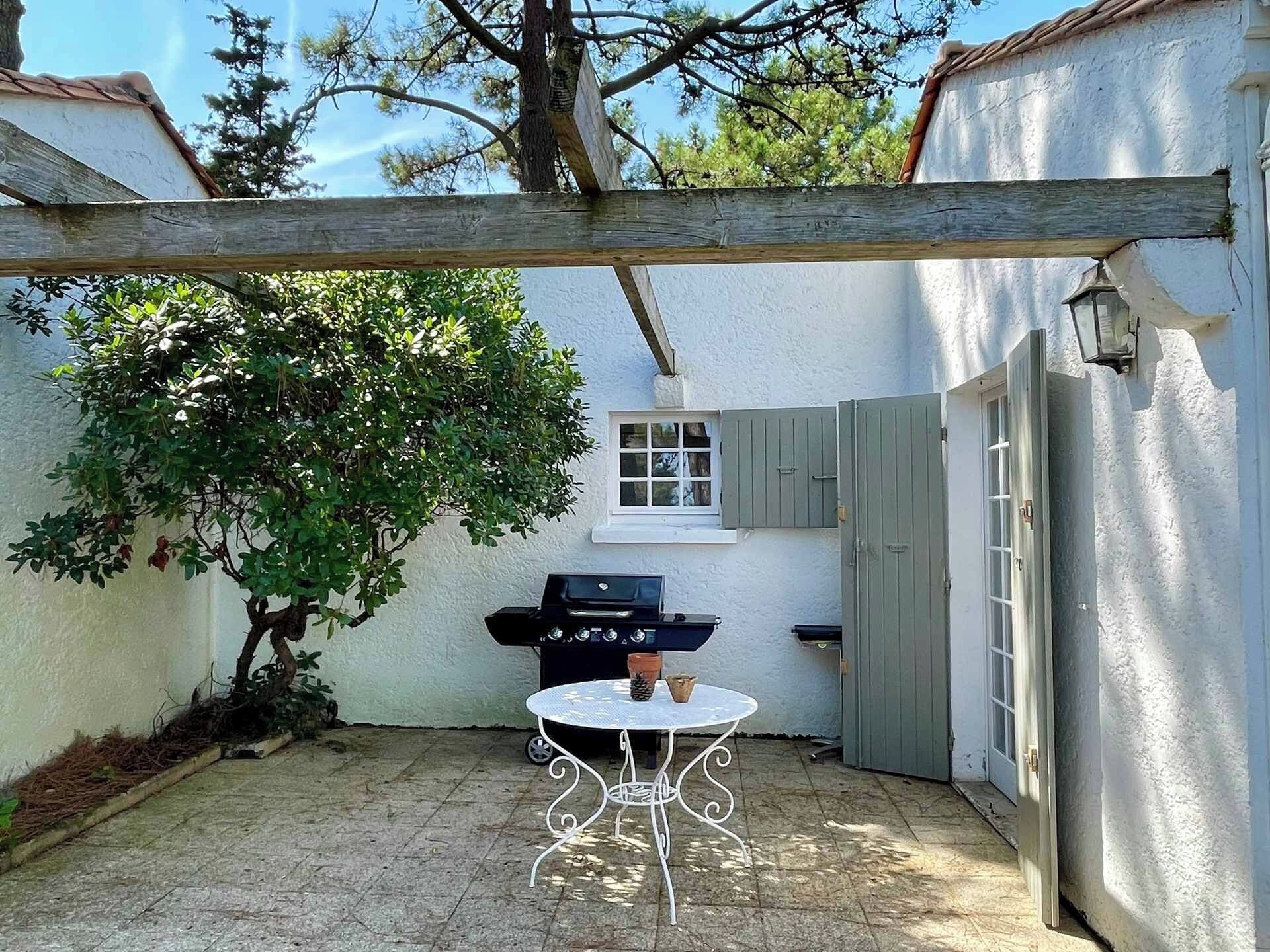 A patio with a barbecue grill, a table, and a pergola.