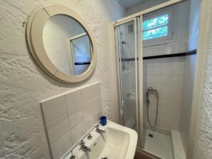 A bathroom with a white sink, a mirror, and a glass-enclosed shower. - Vacation home with wonderful terrace and far-reaching views to the bay (Lège-Cap-Ferret)