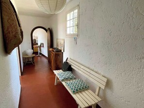 Ein Flur mit einer Bank, einem Schreibtisch mit einem Laptop und einem Fenster.
